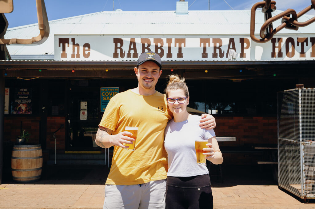 2 people holding beers outside the rabbot trap hotel Albert